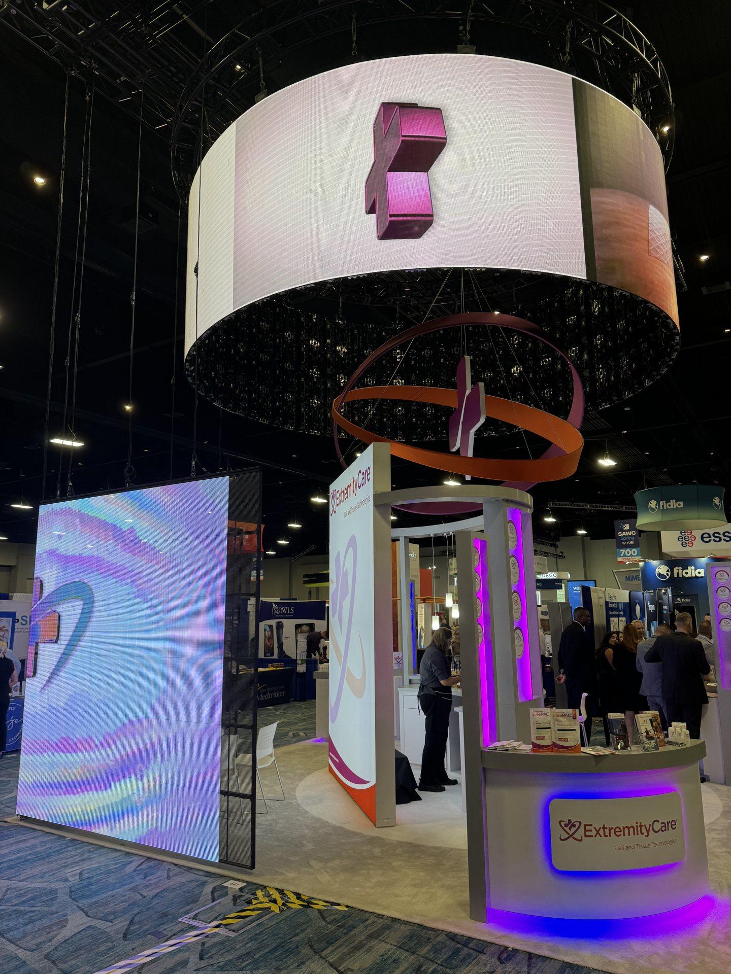 An ExtremityCare island booth with a suspended circular LED ring, built by Lamar Exhibits